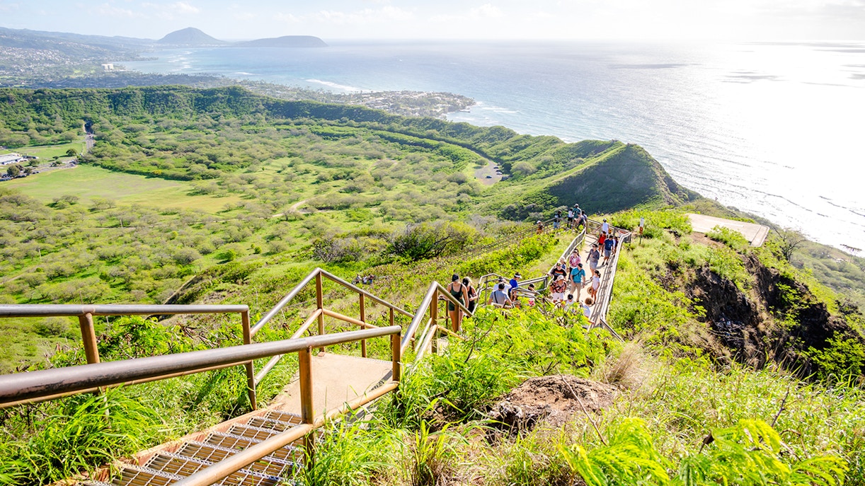 Tourists hiking on Diamond Head trail with ocean and landscape views.