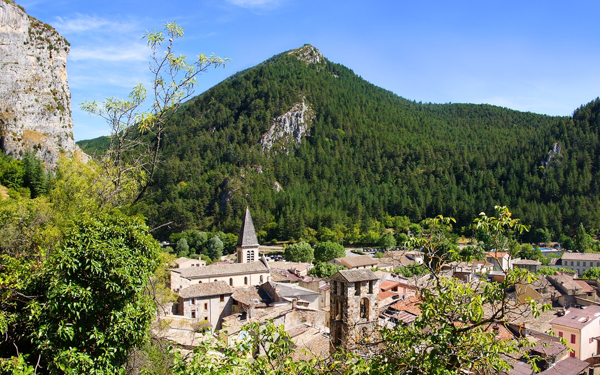 Village nestled in the Gorges du Verdon with a church spire and forested mountains.