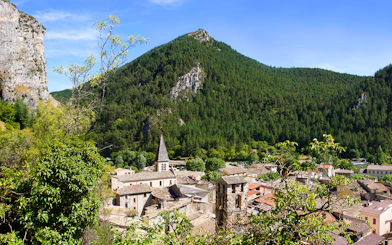 Village nestled in the Gorges du Verdon with a church spire and forested mountains.