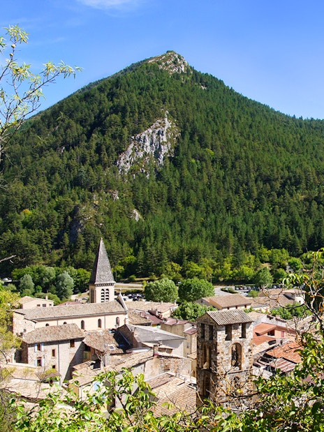 Village nestled in the Gorges du Verdon with a church spire and forested mountains.