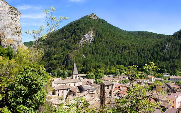 Village nestled in the Gorges du Verdon with a church spire and forested mountains.