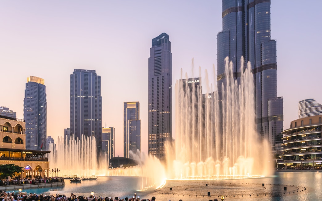 Dubai Fountain show near Burj Khalifa at night with city skyline.