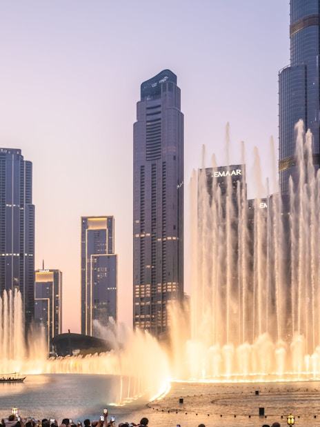 Dubai Fountain show near Burj Khalifa at night with city skyline.