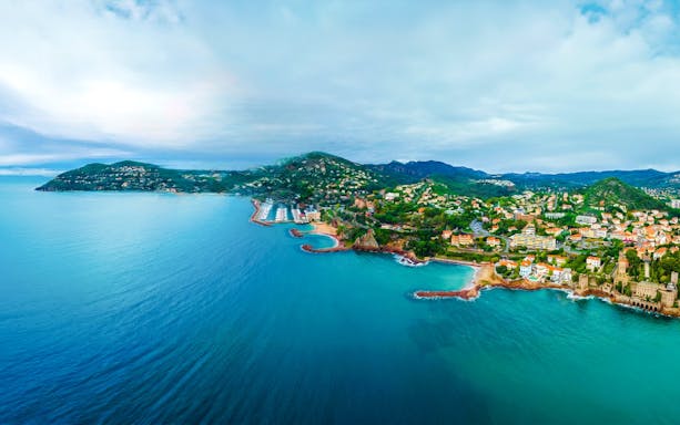 Aerial view of Monaco coastline with lush hills and Mediterranean Sea during a private helicopter tour.