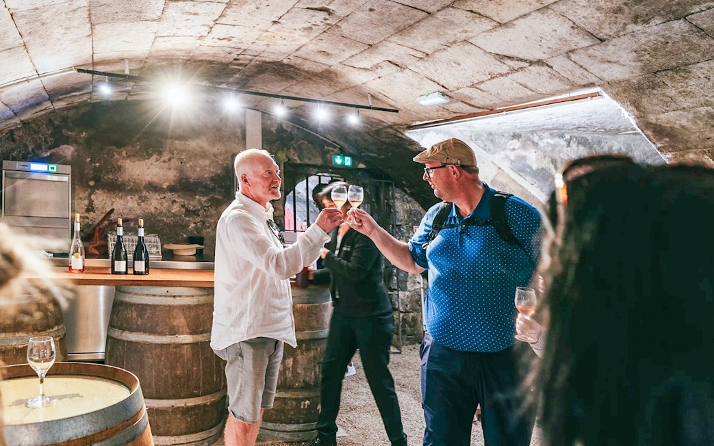 Wine tasting in Chambord Castle cellar with two people toasting glasses.