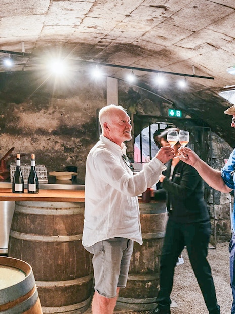 Wine tasting in Chambord Castle cellar with two people toasting glasses.