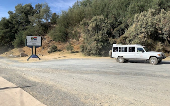 Tour vehicle at Sani Pass border sign, South Africa, on Mountain Splendor tour from Durban.