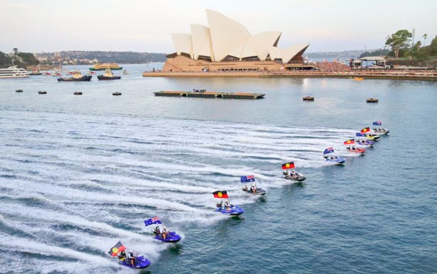 Jet skis with flags near Sydney Opera House during Australia Day cruise.