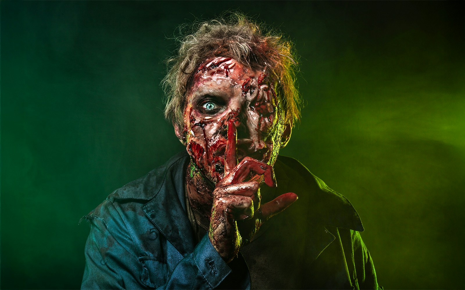 Scary zombie man with decayed face and finger to lips, Halloween theme.