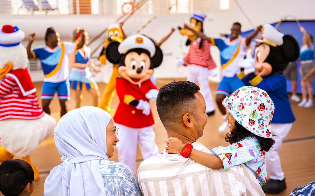 Family enjoying Disney characters at sail away party on Disney Adventure Cruise from Singapore.
