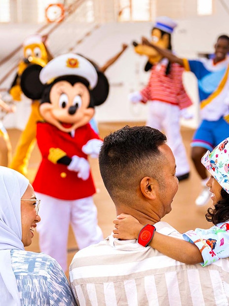 Family enjoying Disney characters at sail away party on Disney Adventure Cruise from Singapore.