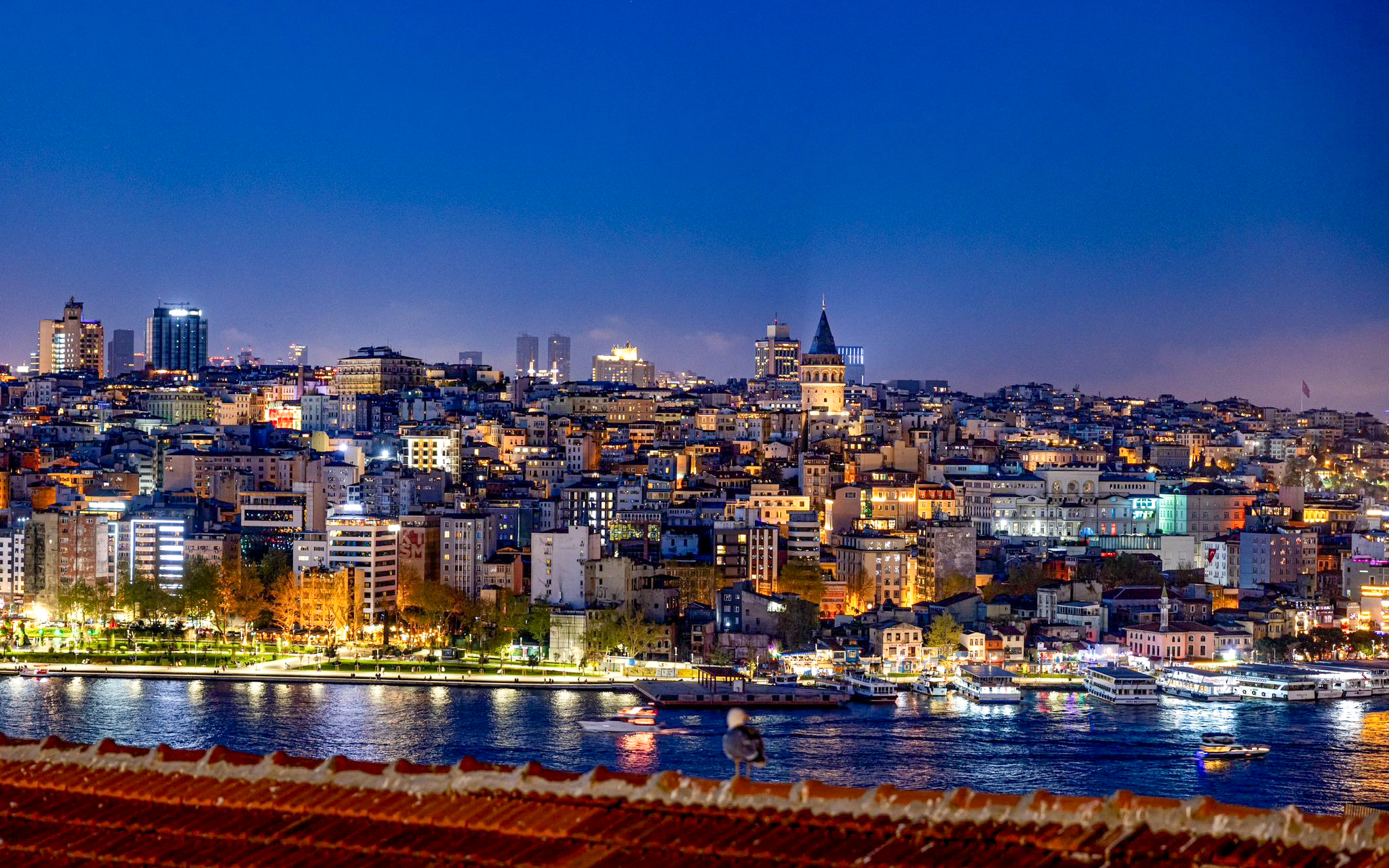 Istanbul skyline with Galata Tower at night, viewed from a rooftop.