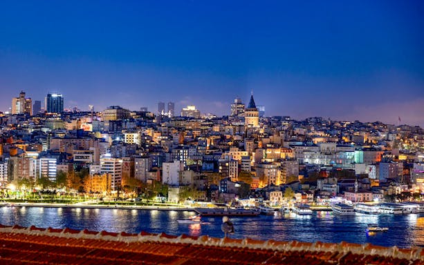 Istanbul skyline with Galata Tower at night, viewed from a rooftop.