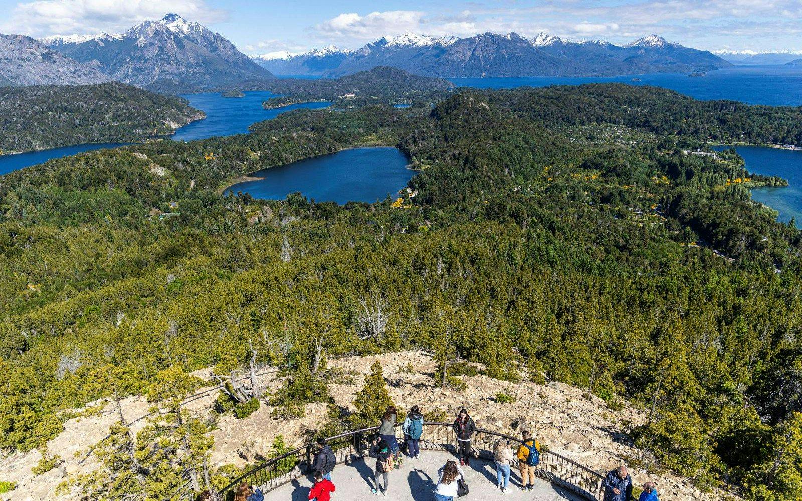 Visitors at Mount Campanario summit enjoying views of lakes and mountains in Argentina.
