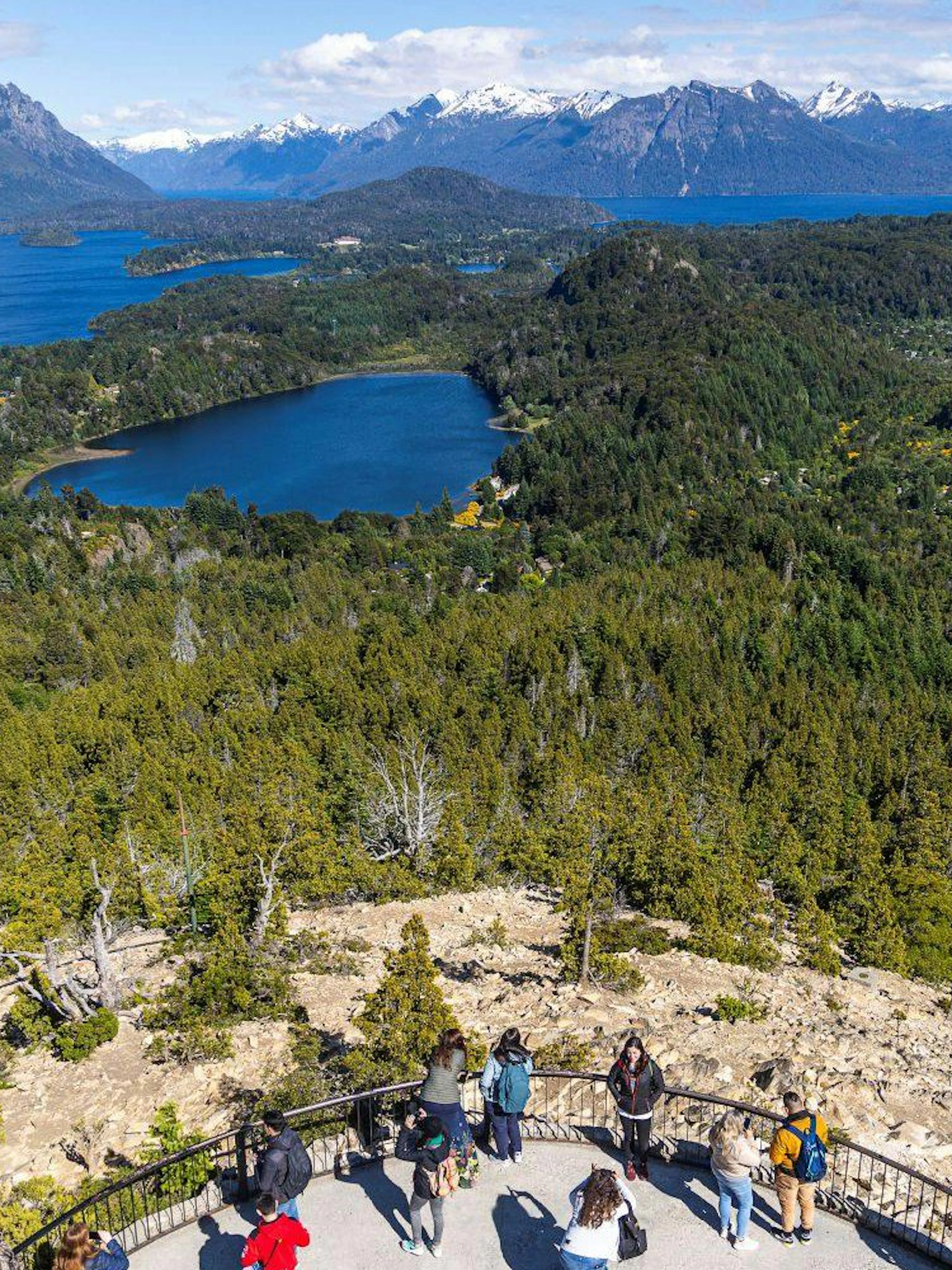 Visitors at Mount Campanario summit enjoying views of lakes and mountains in Argentina.