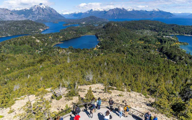 Visitors at Mount Campanario summit enjoying views of lakes and mountains in Argentina.