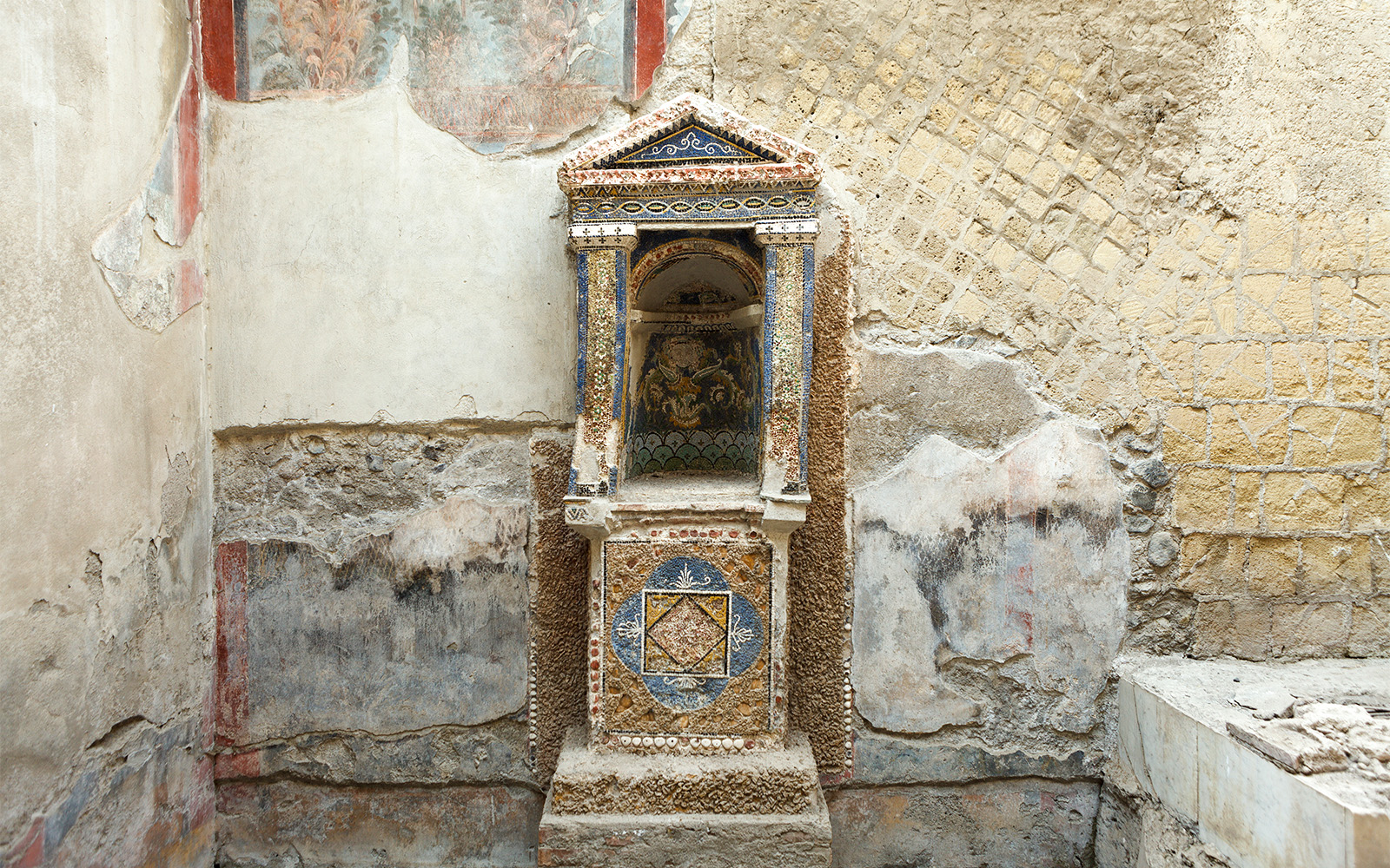 Ancient frescoed niche in Herculaneum with intricate mosaic details.