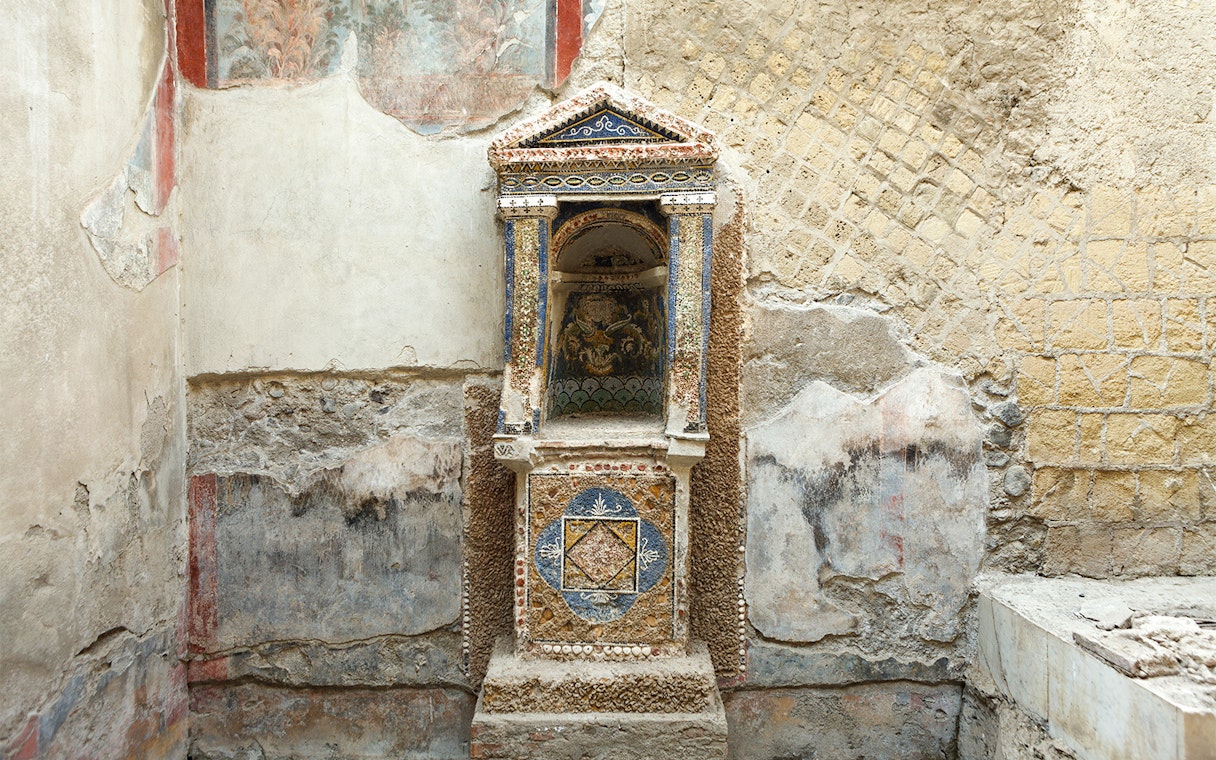 Ancient frescoed niche in Herculaneum with intricate mosaic details.
