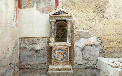 Ancient frescoed niche in Herculaneum with intricate mosaic details.