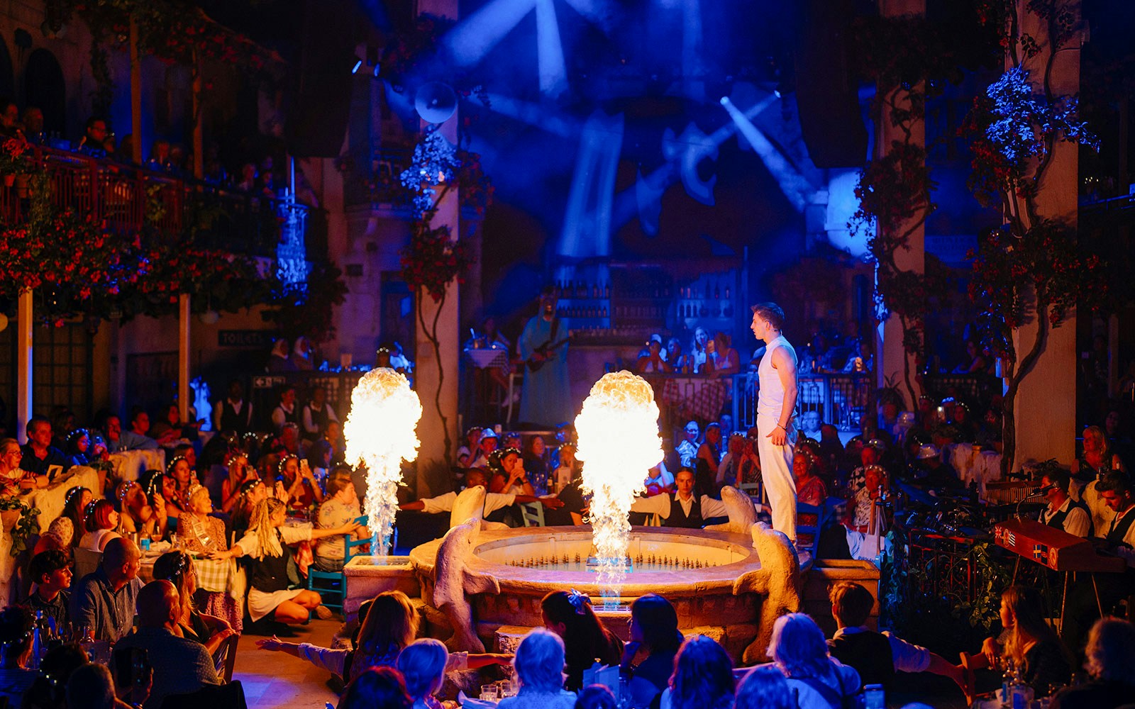 Audience enjoying a live performance with fire effects at Mamma Mia! The Party.