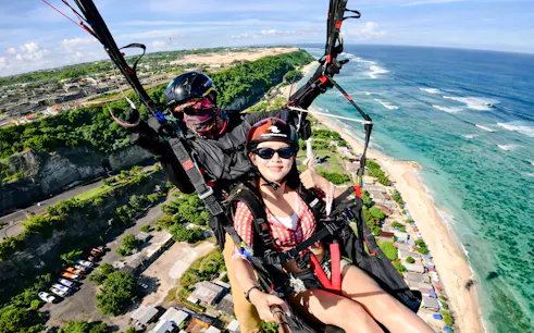 Paragliding over Pandawa Beach with instructor, Bali coastline visible below.