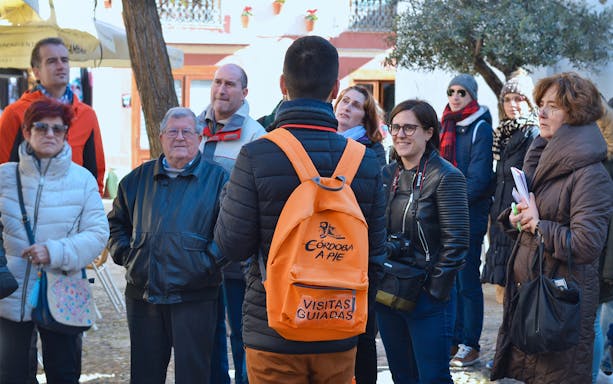Tour group in Córdoba's Jewish Quarter with guide wearing orange backpack.