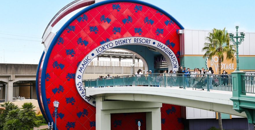 Entrance to Tokyo Disney Resort Japan with visitors on a bridge.