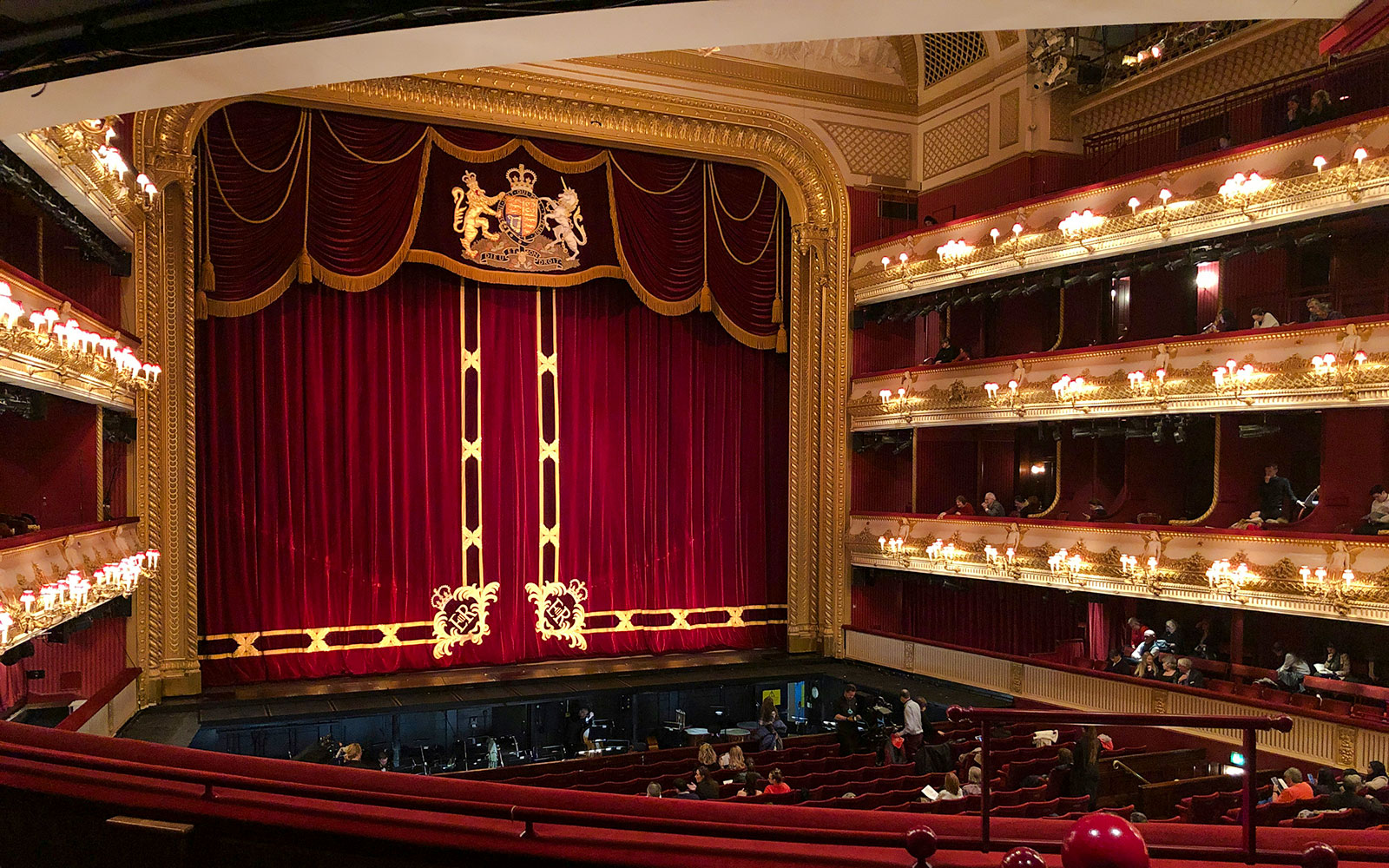 Interior of the Royal Opera House in London with red velvet curtains and ornate balconies.