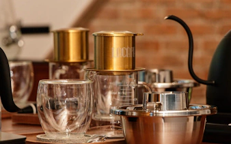 Vietnamese egg coffee preparation setup with glass cups and a traditional drip filter.