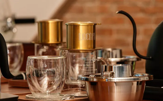 Vietnamese egg coffee preparation setup with glass cups and a traditional drip filter.
