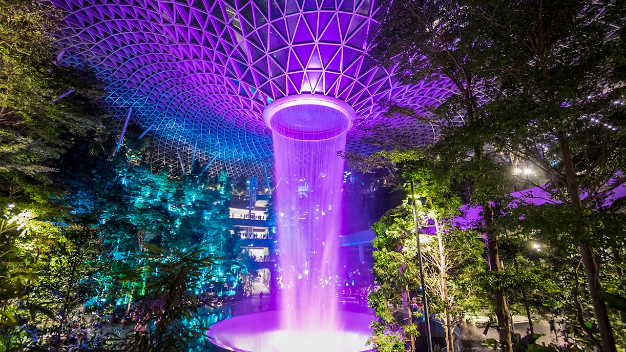 Jewel Changi Rain Vortex indoor waterfall in Singapore's Changi Airport surrounded by lush greenery.