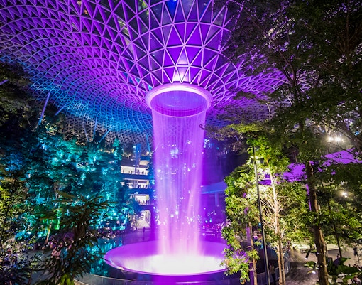 Jewel Changi Rain Vortex in Singapore, central waterfall surrounded by lush greenery.