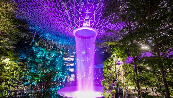 Jewel Changi Rain Vortex in Singapore, central waterfall surrounded by lush greenery.