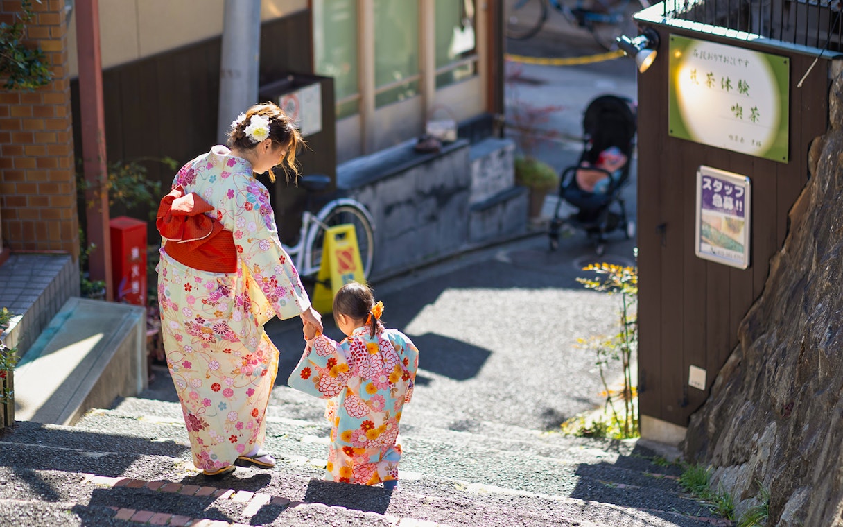 Mother and child in kimonos walking down steps in Kyoto.