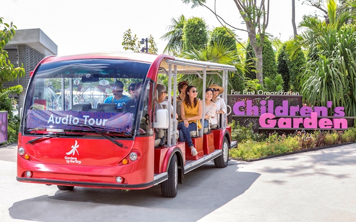 Tram ride at Gardens by the Bay with passengers near Children's Garden sign.