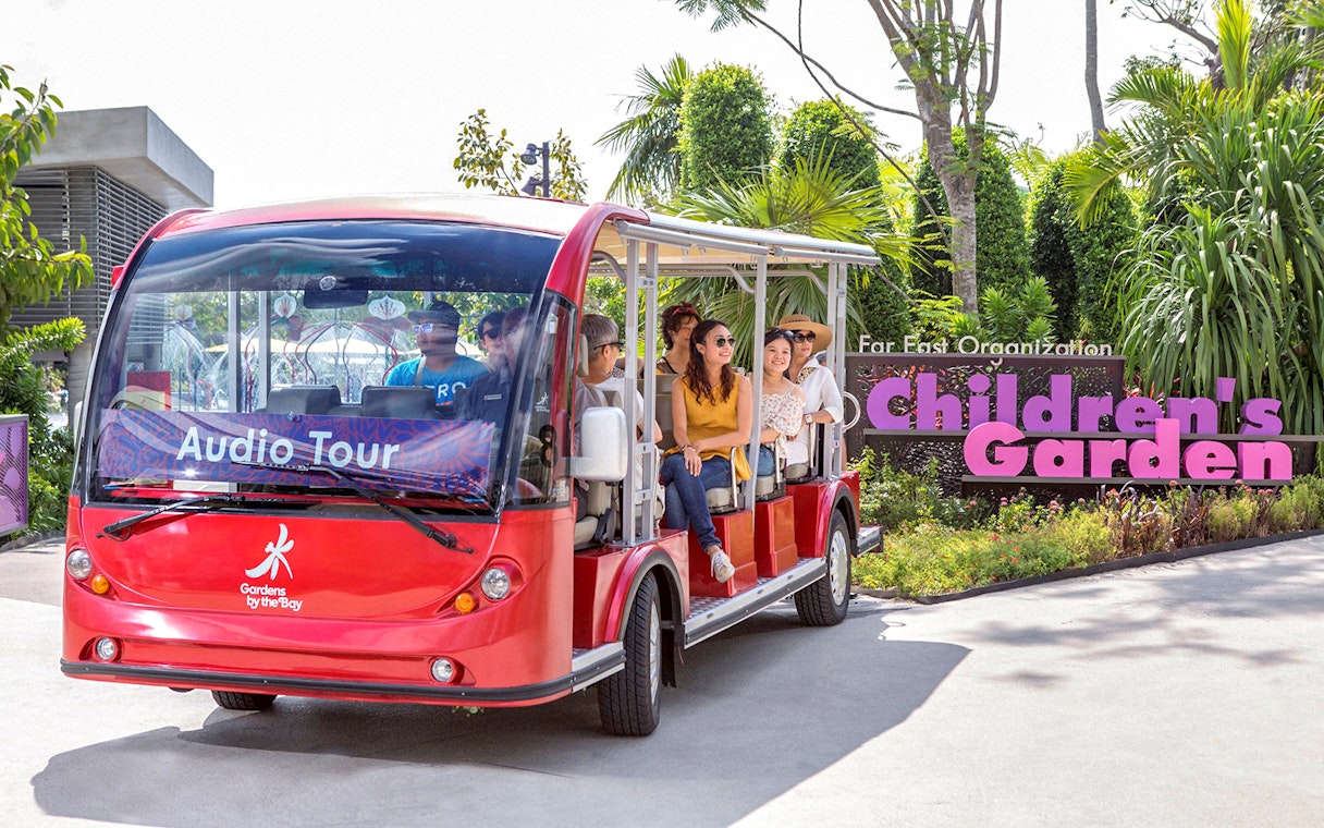 Tram ride at Gardens by the Bay with passengers near Children's Garden sign.