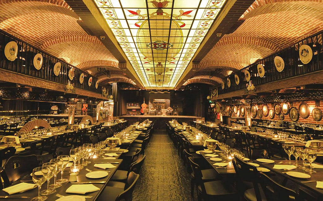 Elegant dining setup at La Ventana Tango Show venue with stage and ornate ceiling.