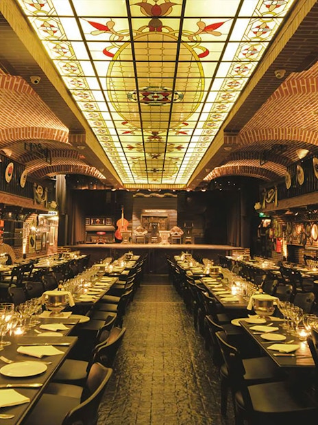 Elegant dining setup at La Ventana Tango Show venue with stage and ornate ceiling.