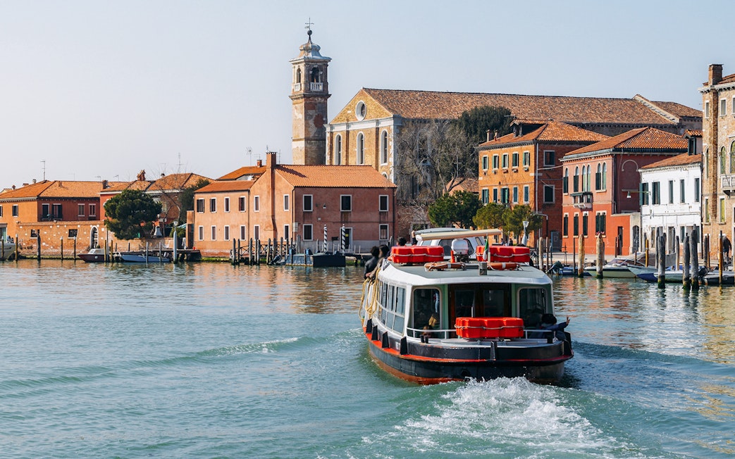 Venice ACTV water bus navigating canal with historic buildings in background.