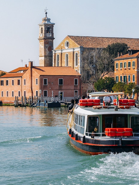 Venice ACTV water bus navigating canal with historic buildings in background.