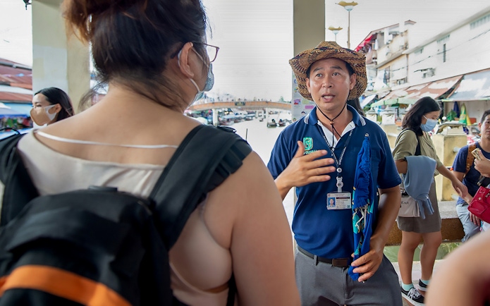 Guide explaining to tourists in Amphawa market area.