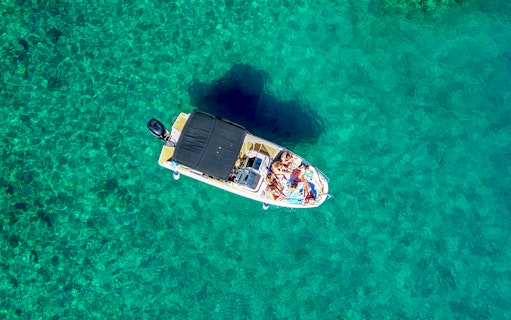 Boat with people on clear turquoise water near Brac Island's secluded bays.