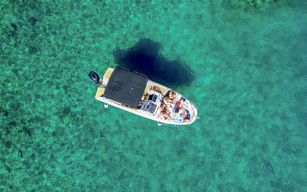 Boat with people on clear turquoise water near Brac Island's secluded bays.