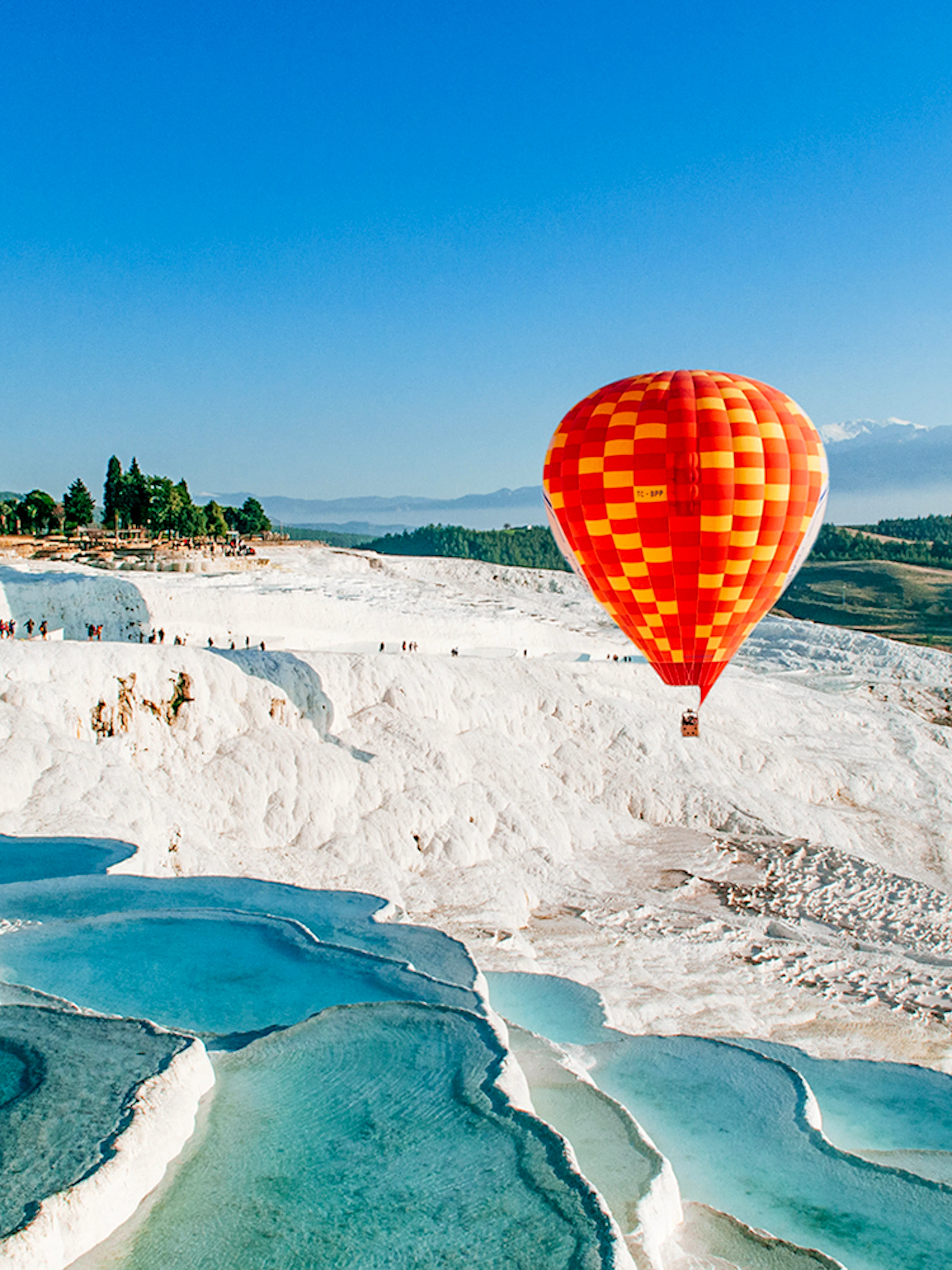 Hot air balloon over Pamukkale's travertine pools and limestone terraces.