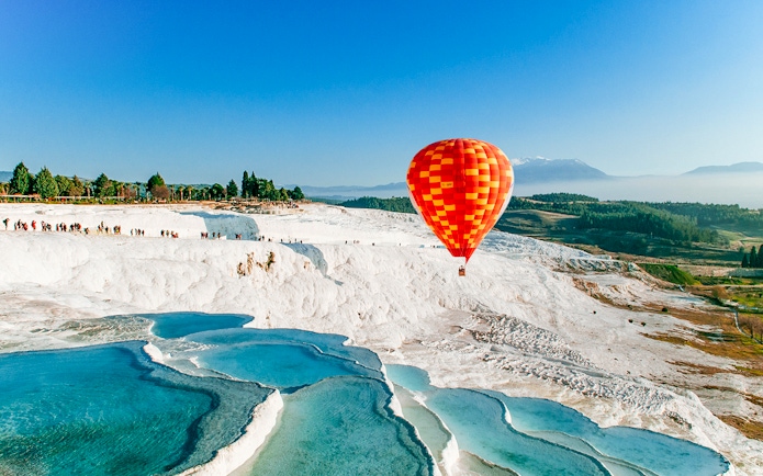 Hot air balloon over Pamukkale's travertine pools and limestone terraces.