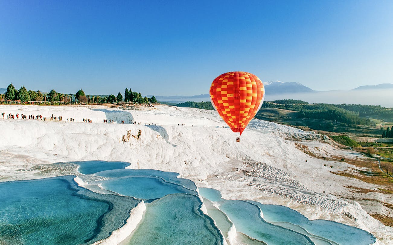 Hot air balloon over Pamukkale's travertine pools and limestone terraces.