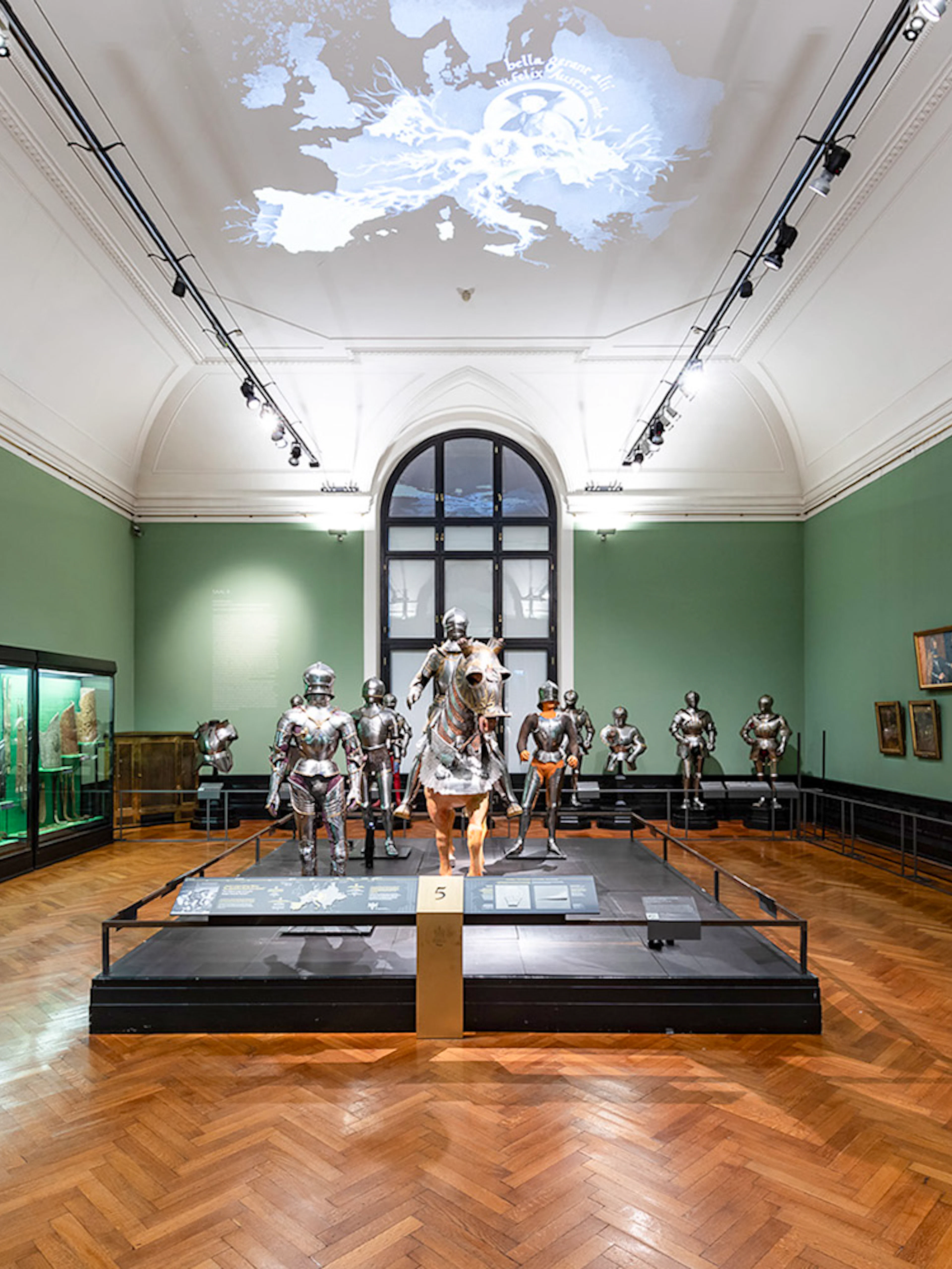 Armory display inside New Hofburg Palace, Vienna, featuring suits of armor and historical artifacts.