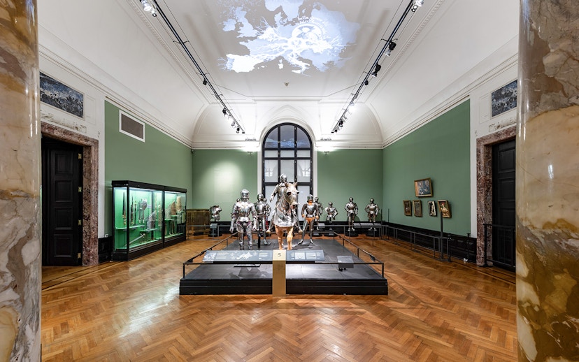 Armory display inside New Hofburg Palace, Vienna, featuring suits of armor and historical artifacts.