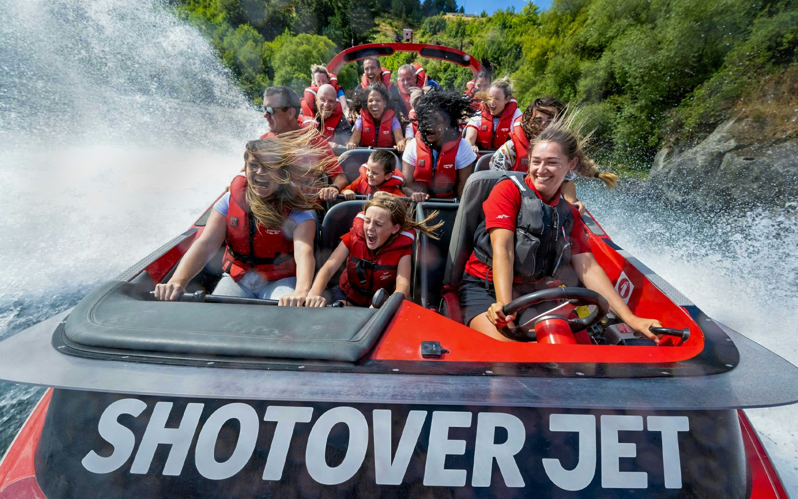 Tourists enjoying a thrilling ride on the Shotover Jet through white water rapids.