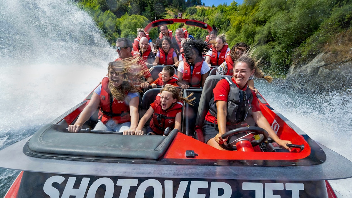 Tourists enjoying a thrilling ride on the Shotover Jet through white water rapids.